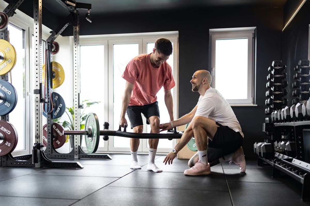 Niklas Kühne begleitet einen Sportler beim Training mit der Langhantel