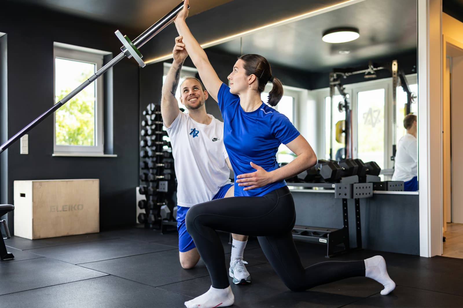 Sportler beim Krafttraining mit Therapeut im Trainingsraum